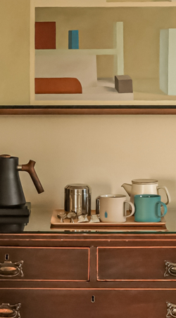antique wooden chest of drawers features a hospitality coffee and tea station setup on its glass-protected top surface at Park Hotel Kenmare, in Kerry, Ireland.